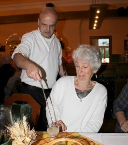 Waiters at a Czech Folkloric dinner top up the wine glasses from a shoulder mounted flagon